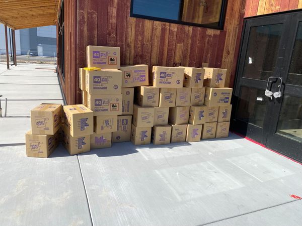 Another angle of a tidy stack of Playdate cartons in front of an under-construction restaurant