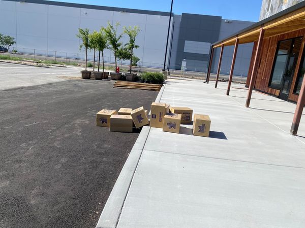 A disorderly array of Playdate cartons strewn half on and half off a sidewalk in front of an under-construction restaurant