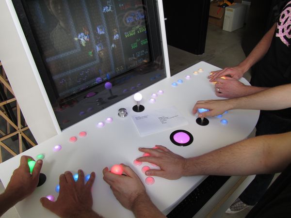 Close-up of four sets of hands playing Gauntlet on the custom Panic MAME arcade cabinet